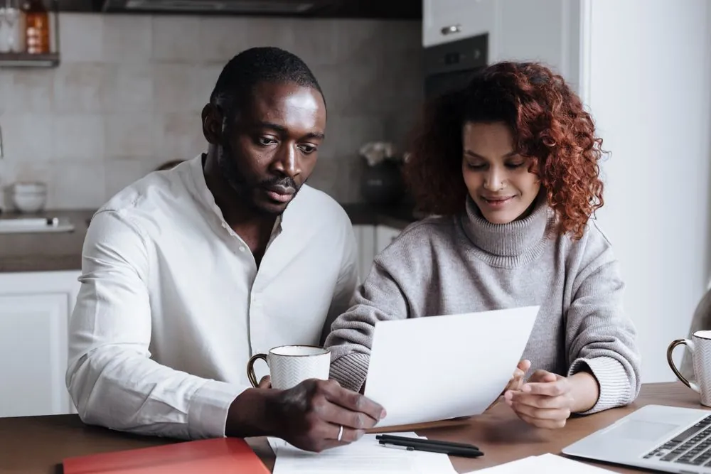 Couple comparing two home insurance quotes at the kitchen table