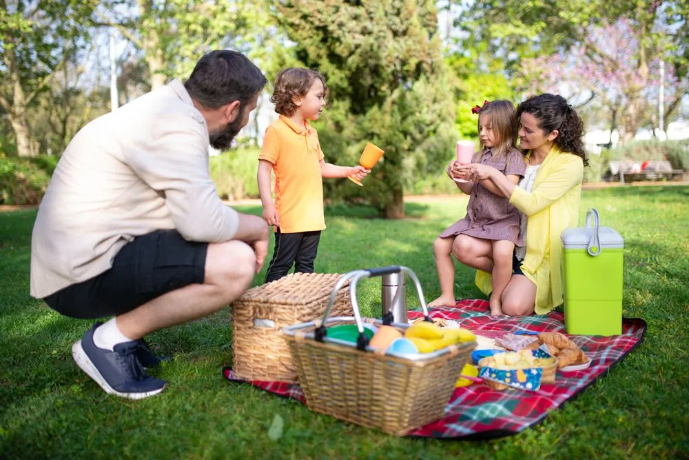 Parents and two young children at a park picnic, the family life insurance is meant to protect